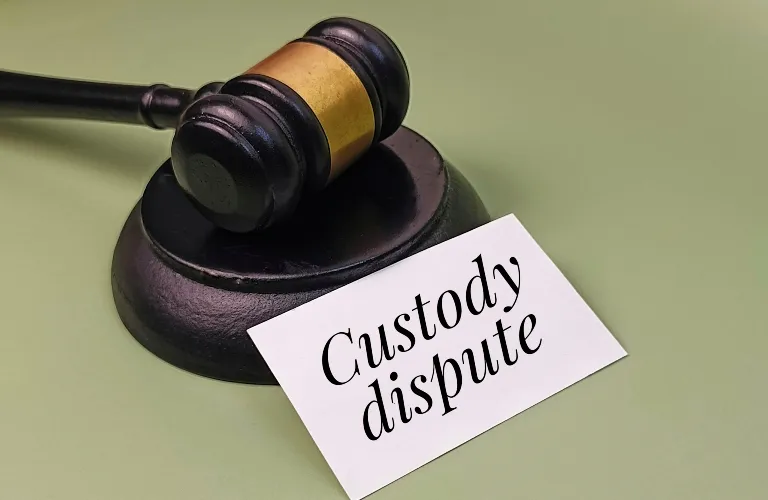 Wooden gavel with brass band resting on sound block next to card reading "Custody dispute